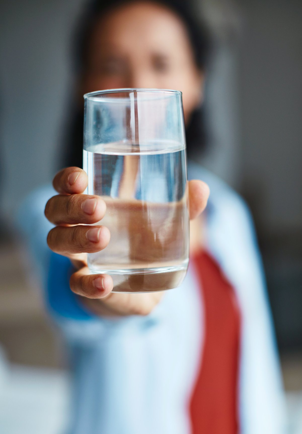 Shot of a woman drinking a glass of water at home